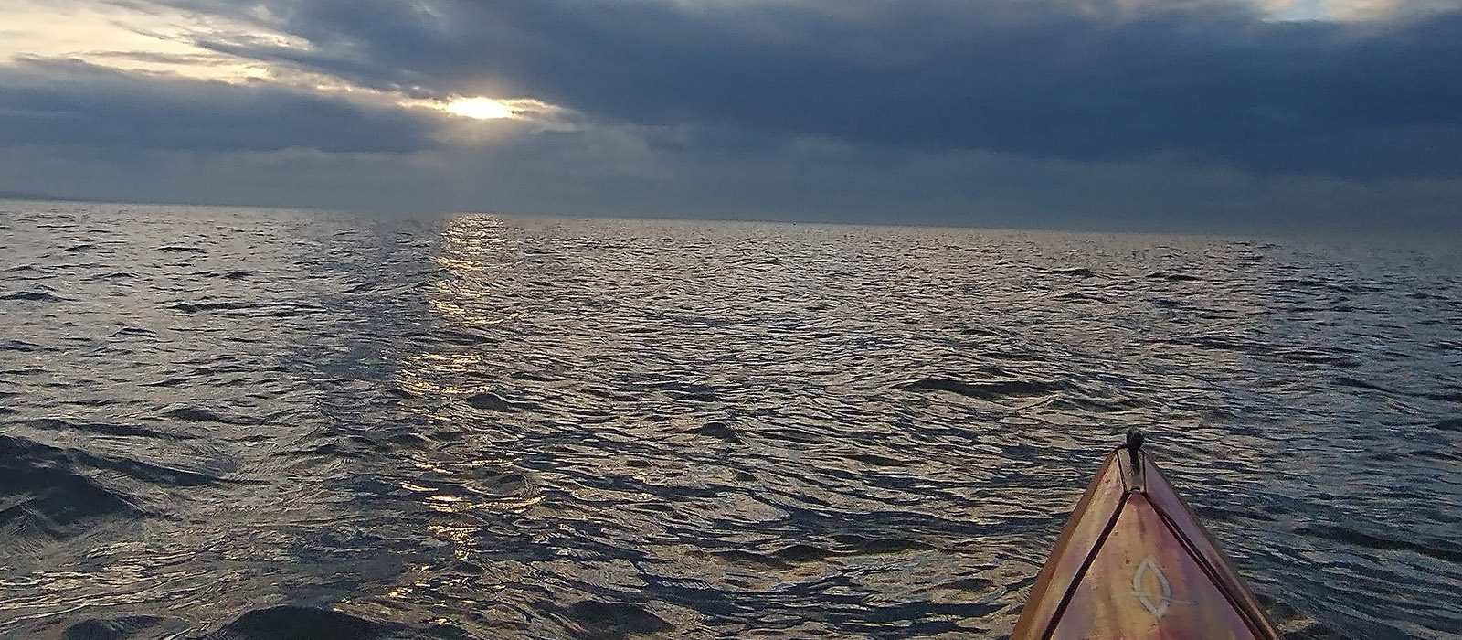 kayak prow pointed out to sea into sundown
